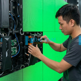 Kỹ thuật viên chuyên nghiệp đang thực hiện thao tác tháo và thay thế một module LED P3 bị lỗi bằng dụng cụ chuyên dụng, phía sau là hệ thống card thu phát tín hiệu.