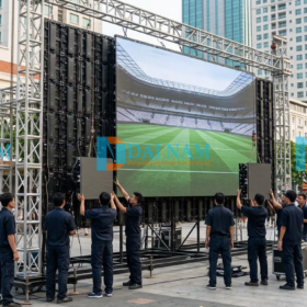 Đội ngũ kỹ thuật viên đang tiến hành lắp đặt các cabinet của màn hình LED ngoài trời cỡ lớn (Outdoor) trên khung truss sắt cho sự kiện fanzone bóng đá tại Việt Nam.